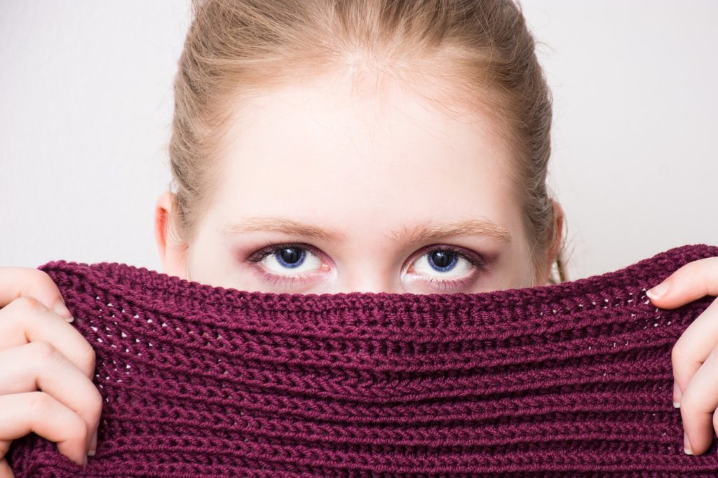 Woman hiding her face below her eyes, behind a purple scarf