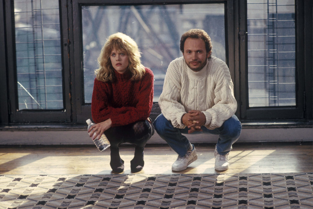 Feel good movie à voir : Image du film Quand Harry Rencontre Sally. Ils sont agenouillés devant un tapis, avec une fenêtre derrière eux. Meg Ryan et Billy Cristal.